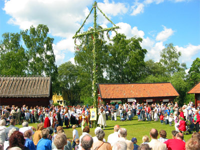 A picture of the maypole and people dancing around it